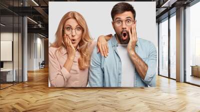 Surprised lovers doesn`t expect to notice someone in house, keep hands on cheeks, see something unbelievable, isolated over white background. People, partners, emotions and reaction concept. Wall mural